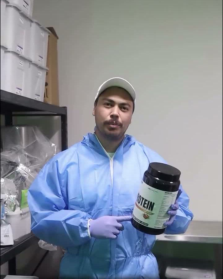 Ascend founder JR in lab coveralls and gloves holding a tub of Ascend protein